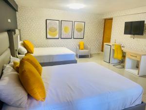 Habitación de hotel con 2 camas con almohadas amarillas en El Paso Hotel, 