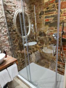 a glass shower in a bathroom with a stone wall at Inside the Wall in Lucca