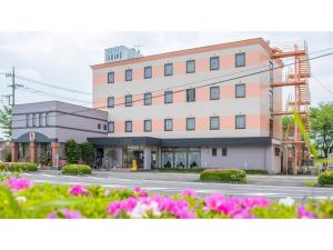 a building on a street with pink flowers at Hotel Tamano - Vacation STAY 41648v in Otawara