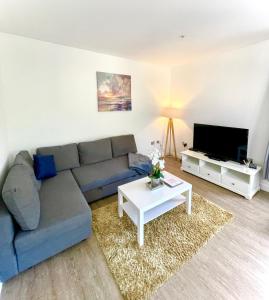 a living room with a couch and a table and a tv at La Fontaine Court Apartments - Aldershot in Aldershot