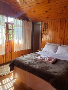 um quarto com uma cama grande e paredes de madeira em Pousada Bem Te Vi Lumiar em Lumiar