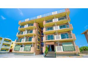 a tall yellow building with green shuttered windows at Hotel Sunset Zanpa - Vacation STAY 50201v in Tokeshi