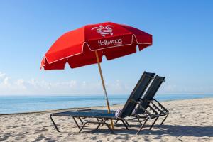 a beach chair with an umbrella on the beach at Costa Hollywood Beach Resort - An All Suite Hotel in Hollywood