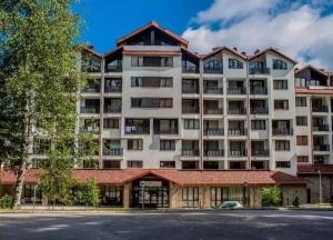 Apartment E23 Borovets Gardens في بوروفتس: عمارة سكنية كبيرة مع موقف للسيارة