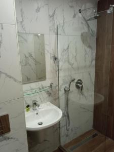 een witte badkamer met een douche en een wastafel bij Apartment E23 Borovets Gardens in Borovets