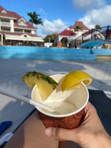 a person holding a drink with a slice of fruit at Studio RDC La Désirade Martinique accès direct plage in Sainte-Luce