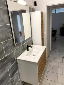 uma casa de banho com um lavatório branco e um espelho. em Appartement moderne, 2 chambres, proche aéroport • CHU • port em Les Abymes