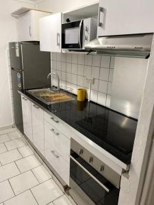 uma cozinha com armários brancos e um balcão preto em Appartement moderne, 2 chambres, proche aéroport • CHU • port em Les Abymes