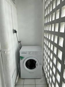 een wasmachine in een kleine kamer met een muur bij Appartement moderne, 2 chambres, proche aéroport • CHU • port in Les Abymes