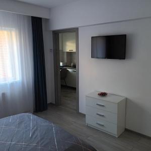 a bedroom with a tv on the wall and a dresser at Studio Acasă in Sibiu