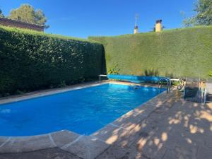 uma grande piscina azul ao lado de uma sebe em Los Álamos, casa de campo cerca de Madrid em Chiloeches