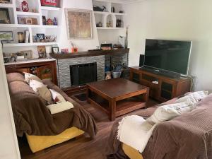 uma sala de estar com um sofá e uma televisão em Los Álamos, casa de campo cerca de Madrid em Chiloeches