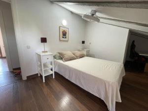 um quarto com uma cama branca e uma mesa de cabeceira com um candeeiro em Los Álamos, casa de campo cerca de Madrid em Chiloeches