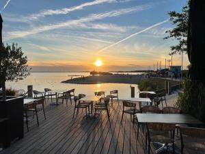 a group of tables and chairs on a deck with the sunset at Copenhagen Residence in Harderwijk