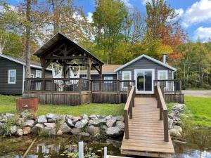 une maison avec un pont en bois sur un étang dans l'établissement Bespoke Lake Cottage, à New Minas