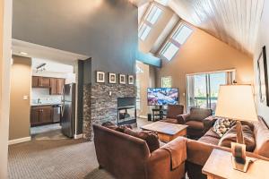 uma sala de estar com mobiliário de couro e uma lareira de pedra em Snowbird by Elevate Vacations em Whistler
