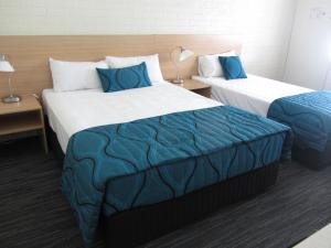 a hotel room with two beds with blue pillows at Urangan Motor Inn in Hervey Bay