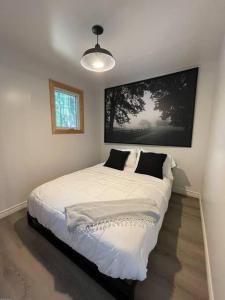 Leland’s Lakehouse في ولف فيل: غرفة نوم بسرير ذو شراشف بيضاء ومخدات سوداء