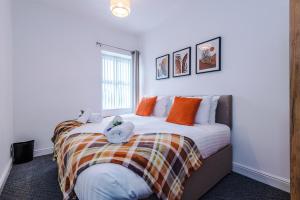 1 dormitorio con 1 cama con almohadas de color naranja y ventana en Spacious 3-Bed house in Stoke by 53 Degrees Property, Ideal for Long Stays, FREE Parking - Sleeps 6, en Stoke on Trent