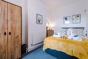 1 dormitorio con 1 cama con colcha amarilla en Spacious 3-Bed house in Stoke by 53 Degrees Property, Ideal for Long Stays, FREE Parking - Sleeps 6, en Stoke on Trent