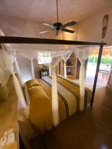 1 dormitorio con cama con dosel y ventilador de techo en Troncones Point Hostel, en Troncones