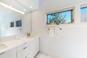 a white bathroom with two sinks and a window at Unveil Vail in Vail +36 photos