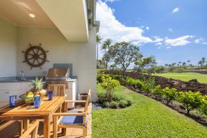 a patio with a wooden table and chairs and a yard at Fairways at Mauna Lani by South Kohala Management in Waikoloa