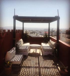 a patio with white benches on a roof at Charmant riad pour familles ou groupes - Dar Mama in Essaouira