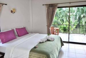 1 dormitorio con 1 cama grande con almohadas rosas y balcón en Sawasdee Home Stay Resort & Pool, en Khao Lak