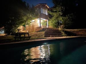 uma piscina à noite com uma casa ao fundo em Domaine de Ferrières Haut em Bruniquel