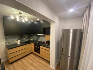 a kitchen with a stainless steel refrigerator and wooden cabinets at Sweethome Ciocana in Chişinău