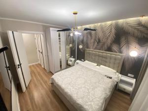 a bedroom with a white bed and a wall with a leaf pattern at Sweethome Ciocana in Chişinău
