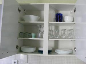a kitchen shelf with dishes and glasses on it at Studio Continental côté jardin in Vittel +12 photos