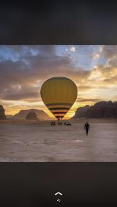 una persona caminando delante de un globo de aire caliente en Mountain Magic Camp Wadi Rum, en Wadi Rum