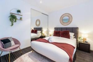 um quarto com uma cama, um espelho e uma cadeira em Trendy 2 bed 2 bath Apartment - Heart of St Kilda em Melbourne