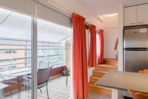 a kitchen with red curtains and a balcony with a table at Puerto Madero a metros del Faena in Buenos Aires