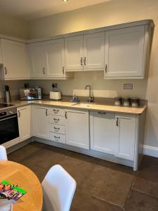 a kitchen with white cabinets and a table at Horse Market Cottage Kirkby Lonsdale in Kirkby Lonsdale