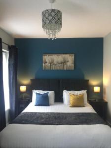 a bedroom with a bed with blue walls and a chandelier at The Rooms at The Spout in Kilcullen