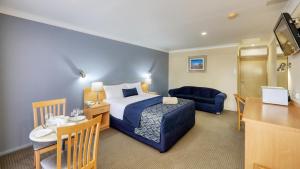 a hotel room with a bed and a table and a couch at Edward Parry Motel and Apartments in Tamworth