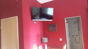 a bathroom with a television on a red wall at Gasthaus Krone in Pforzheim