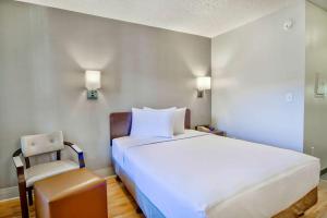 a bedroom with a large white bed and a chair at Studio 6-Phoenix, AZ - Deer Valley in Phoenix