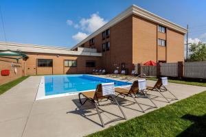 a swimming pool with chairs in front of a building at Best Western Plus Wooster Hotel & Conference Center in Wooster