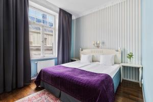 a bedroom with a large bed with a purple blanket at Best Western Hotel Bentleys in Stockholm