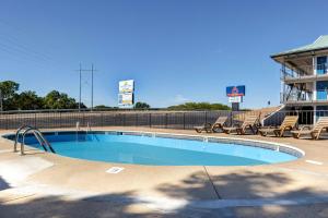 a swimming pool with chairs and a building at Motel 6 Branson West, MO - Silver Dollar City in Branson West