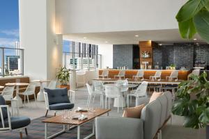 un restaurante con mesas y sillas blancas y un bar en YOTEL Miami en Miami