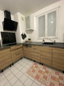 een keuken met houten kasten en een groot raam bij Appartement Chaville in Chaville