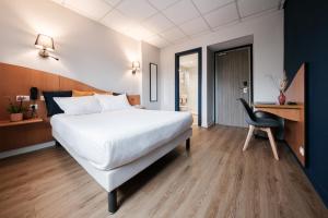 a bedroom with a large white bed and a desk at Hôtel du Parc in Thionville