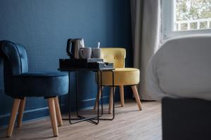 una mesa y 2 sillas en una habitación con una pared en Hôtel du Parc en Thionville