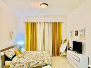 1 dormitorio con cama y cortina amarilla en Rixos Beach Apartment en Ras al-Khaimah