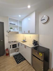 a kitchen with white cabinets and a sink and a clock at Close to Polymedic Medical Plaza with FREE Wi-fi & Netflix in Cagayan de Oro